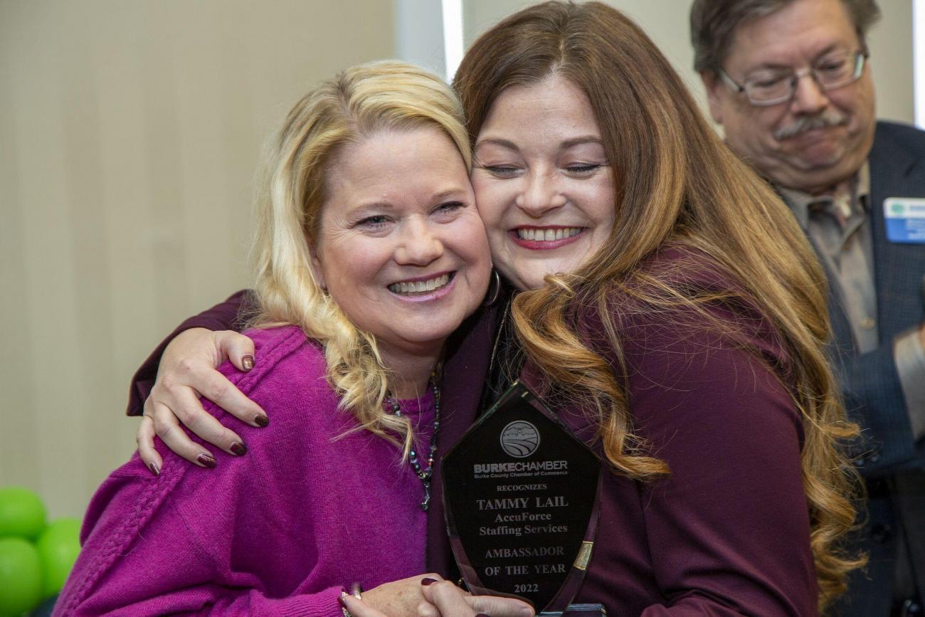 tammy laid hugging a woman while holding her award