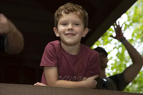 Little boy at camp on porch looking at camera.