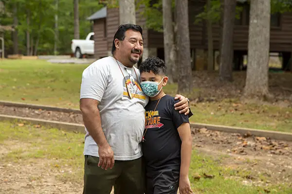 Man hugs his son goodbye as he starts camp.