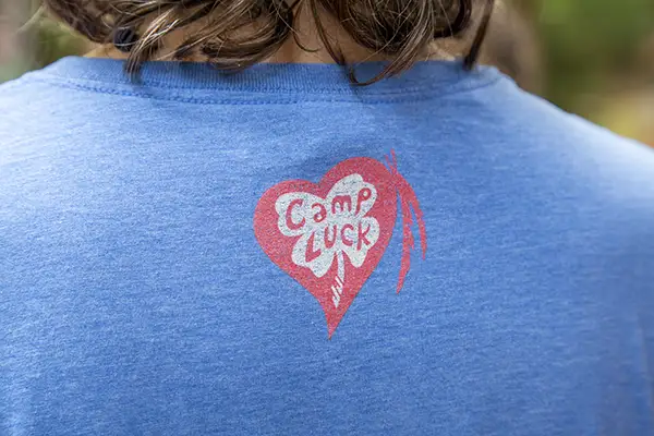 Kid with Camp Luck shirt on displaying logo on back.