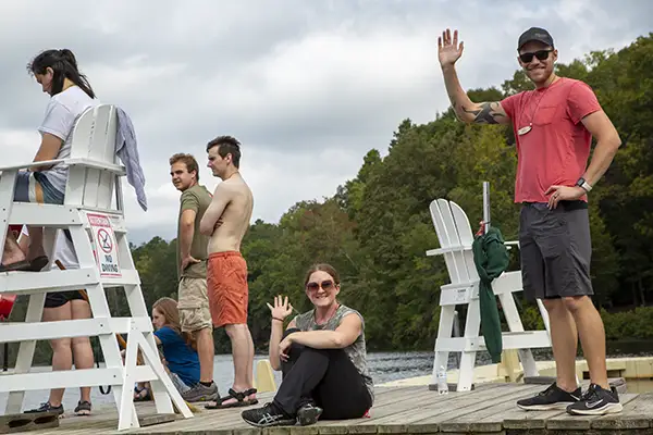 Camp goers on dock wave to the camera man.