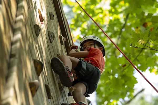 Little boy at camp, climbing rock wall.
