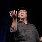 Mike Rowe is gestering towards the crowd with is right hand