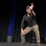 Mike Rowe crouching with his left hand up high