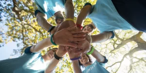 Group of diverse people bringing hands together from a low camera angle.